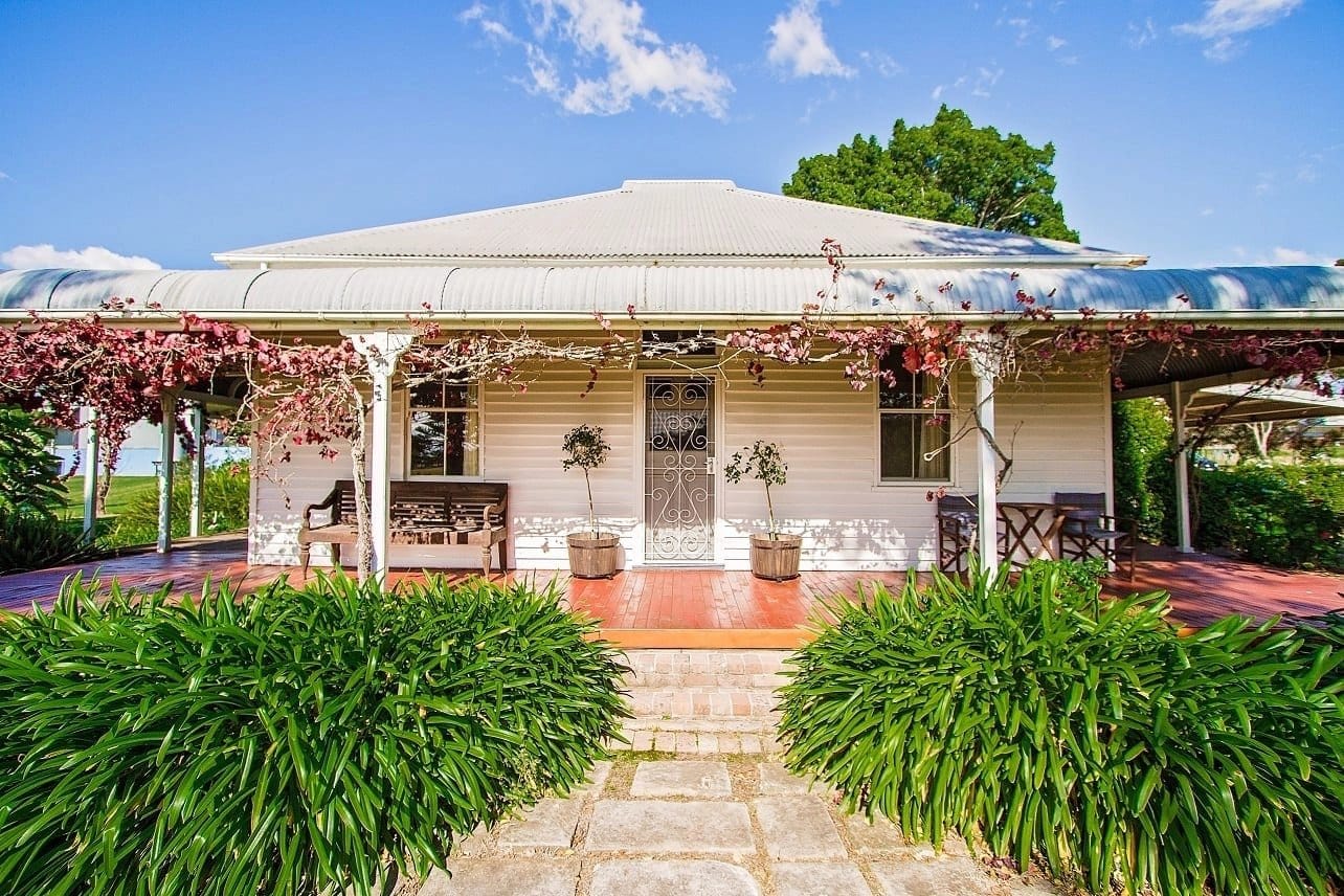 White cottage with red brick path and flowering vines