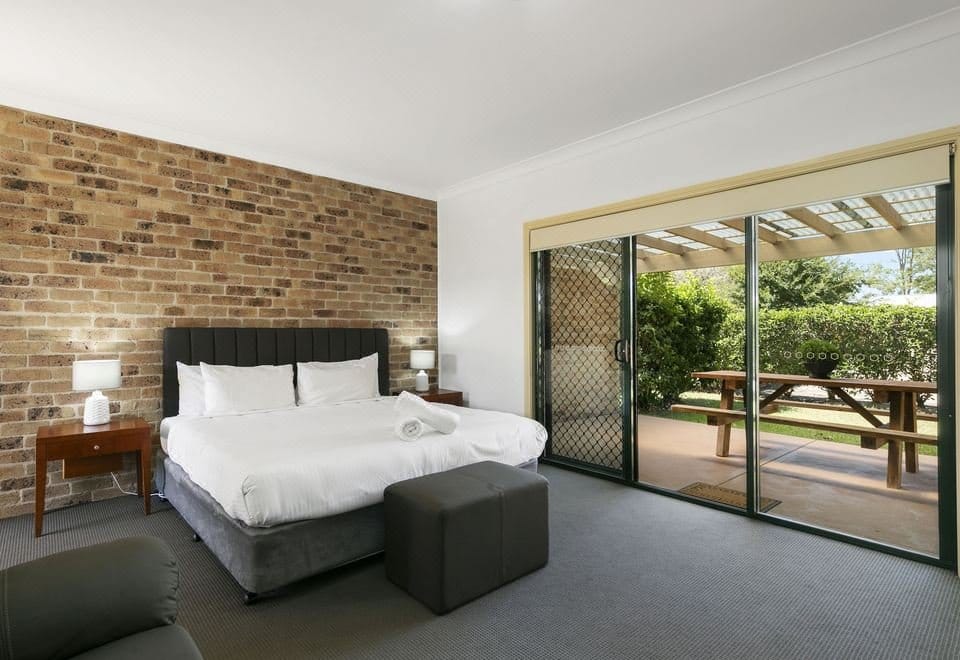 Guest room with brick feature wall and outdoor patio at Potters Hotel Brewery Resort, Nulkaba, Hunter Valley