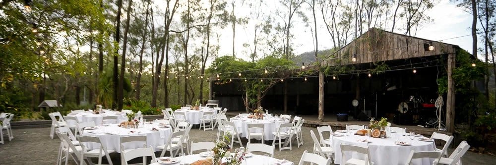 Outdoor event venue with tables under wooden shelter