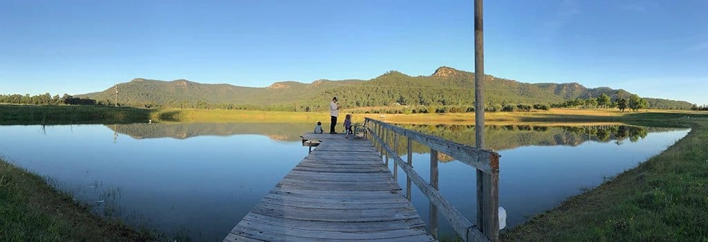 Wooden jetty extending into reflective water landscape