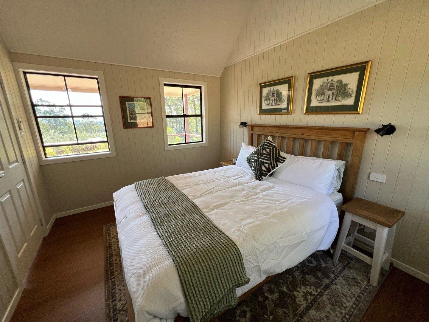 Queen bedroom with timber furniture and a window view over paddocks at Rocklee Grove