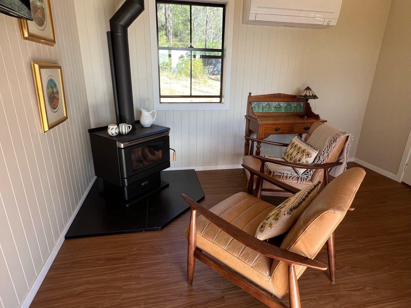 Lounge room with a wood fireplace and armchairs at Rocklee Grove