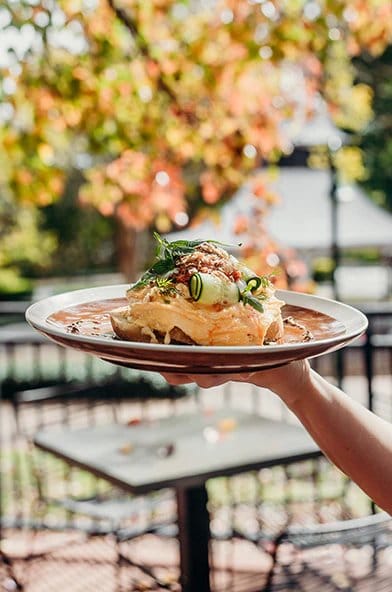 Plated dish held over an outdoor table at Ronnie's, Pokolbin