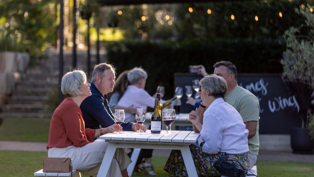 Evening outdoor gathering with people at table under string lights