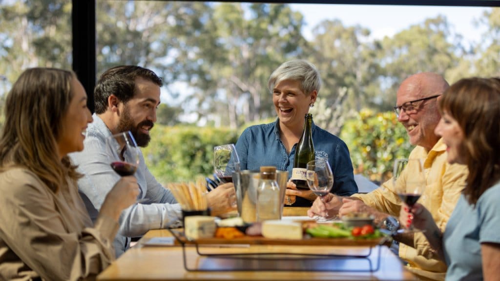 Group of people tasting wine outdoors with food and glasses