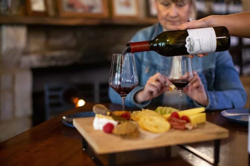 Red wine being poured for a guest beside cheese and charcuterie board at Savannah Estate, Pokolbin, Hunter Valley