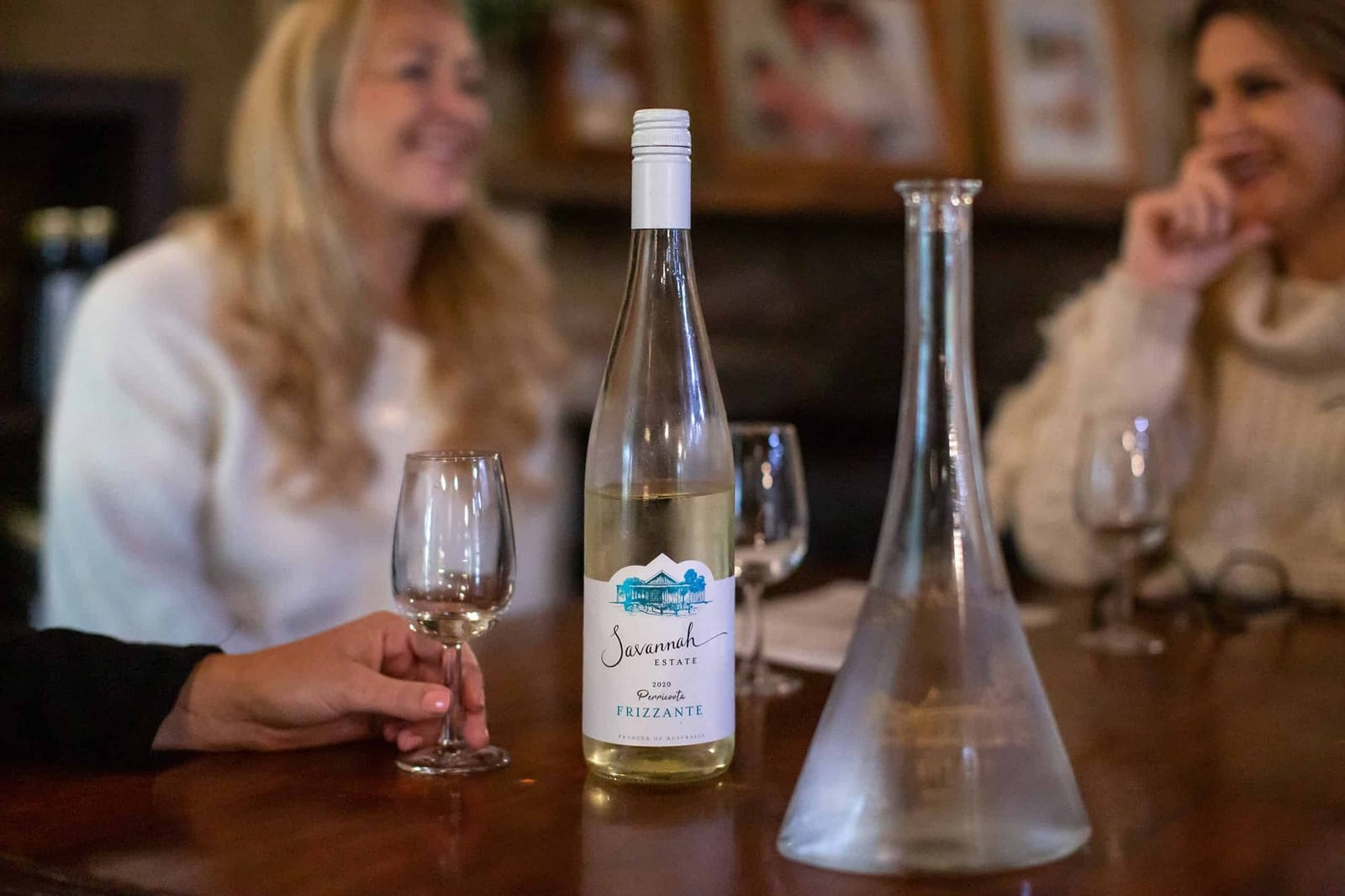 A bottle of Savannah Estate Frizzante on the tasting bench with guests behind
