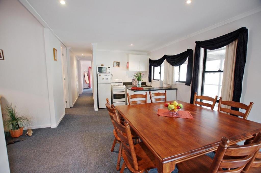 Open kitchen and dining table seating six, with a hallway leading to the bedrooms.