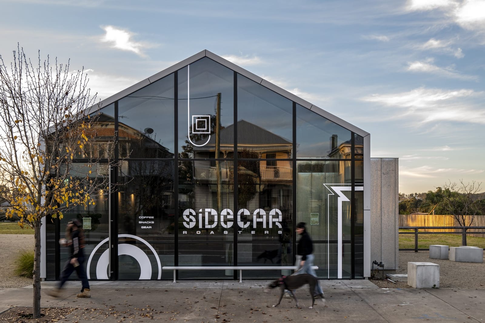 Glass-gabled building at dusk with people walking past at Sidecar Roasters, Branxton, Hunter Valley