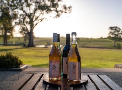 Squires Vineyard wine bottles on an outdoor table with vineyard view, Belford, Hunter Valley