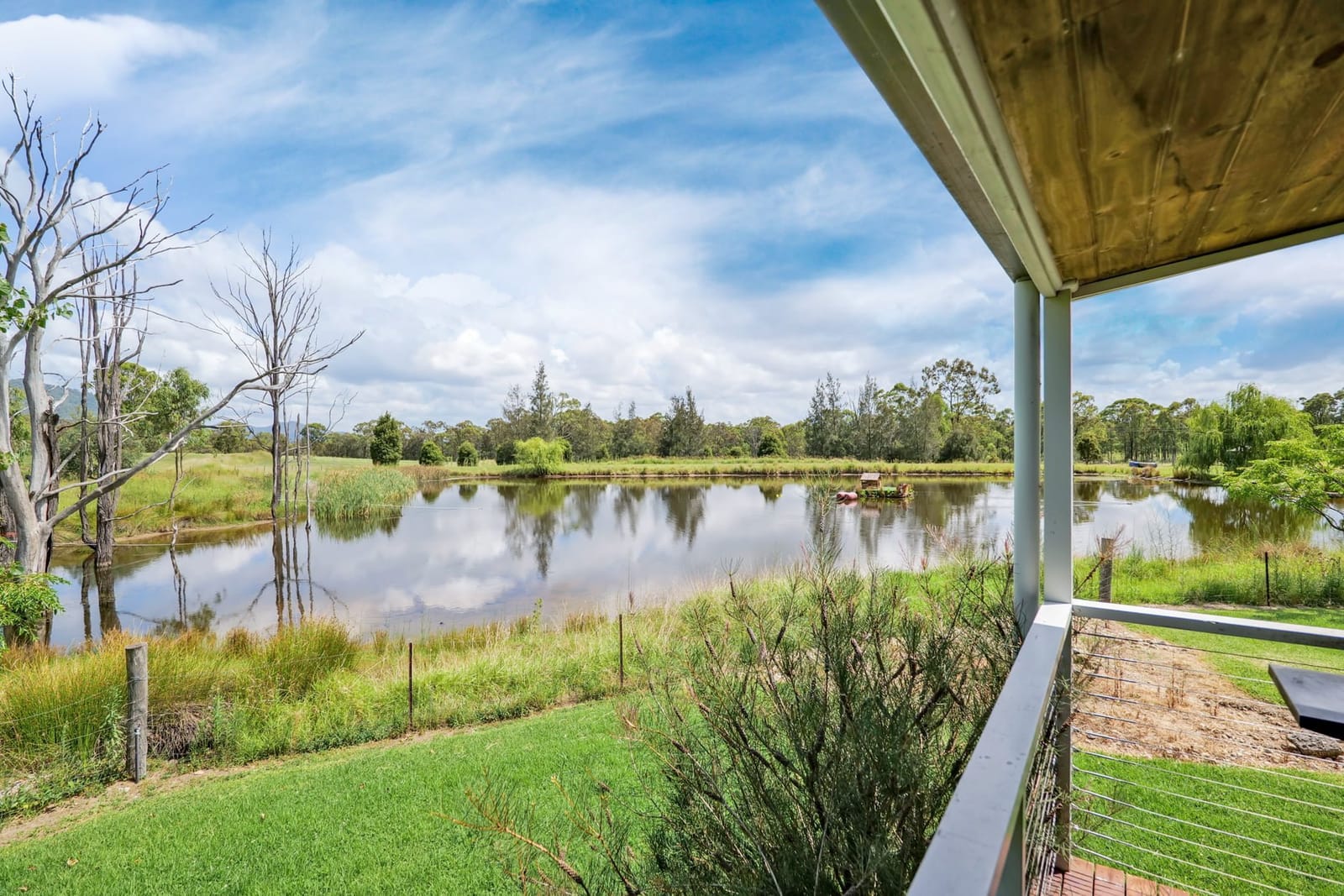 A farm dam and open paddocks seen from a cottage veranda