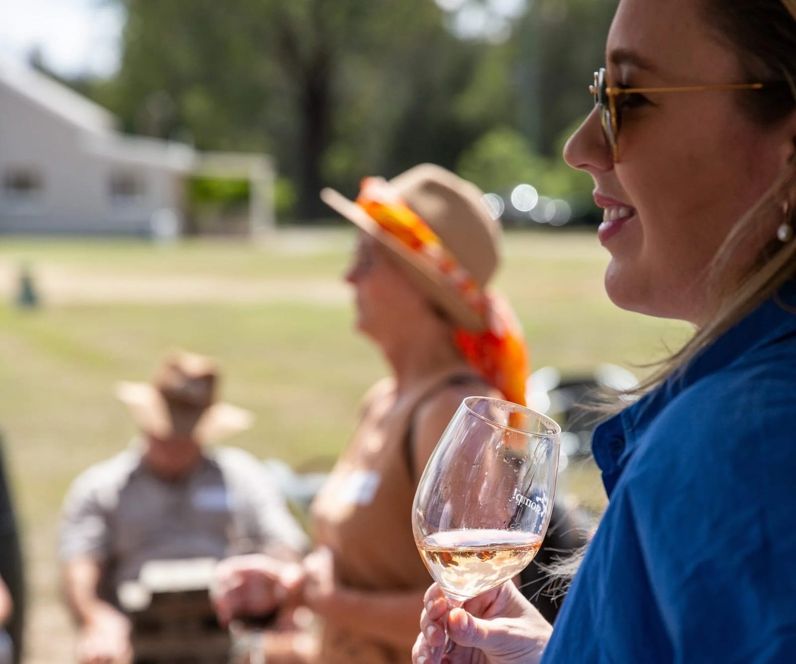 Woman holding wine glass at outdoor gathering with guests
