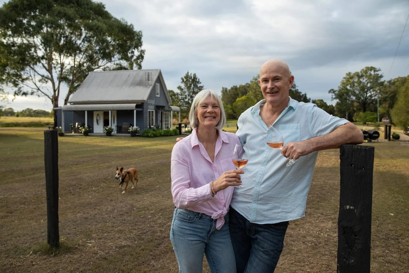 Man and woman holding wine glasses in front of country house at Stomp, Lovedale, Hunter Valley