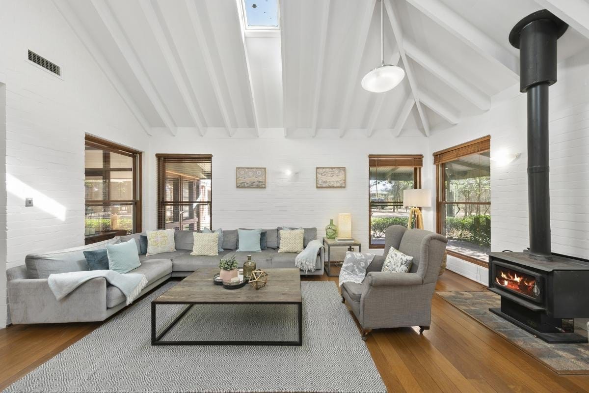 A vaulted living room with a grey sectional sofa and wood-burning stove
