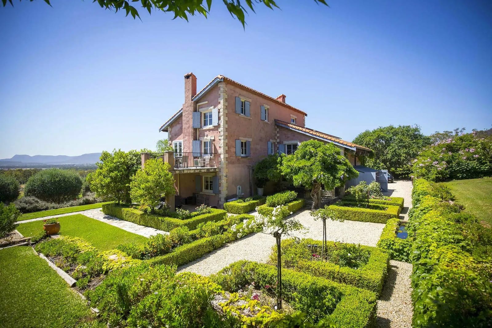 Terracotta villa surrounded by formal hedged gardens