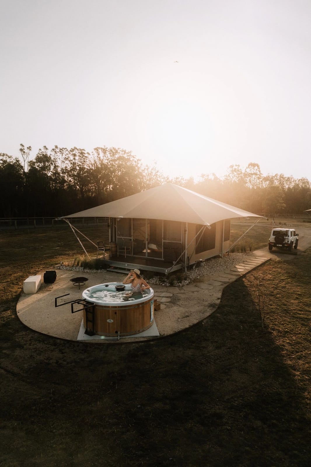 A glamping tent with an outdoor hot tub at sunset