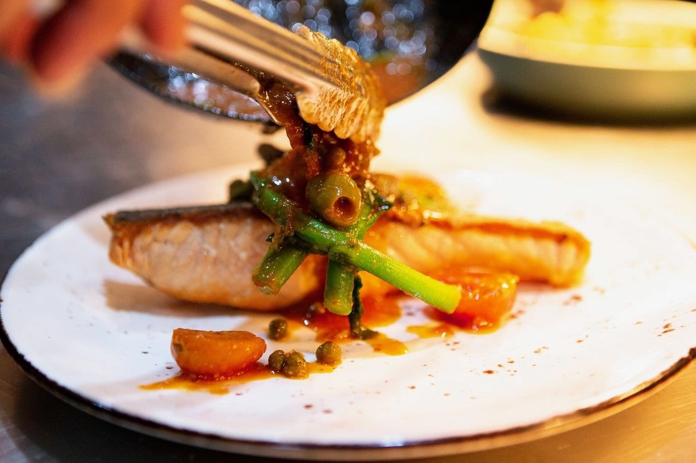 A plated fish dish with charred asparagus, olives and cherry tomatoes at The Italian Cottage, Pokolbin