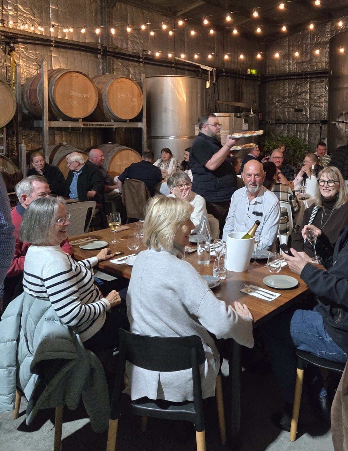 Indoor event with diners at long tables under hanging lights