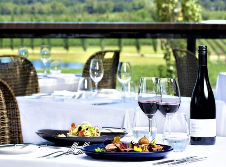 Outdoor dining with plated dishes, wine and vineyard views at The Mill Restaurant, Pokolbin, Hunter Valley