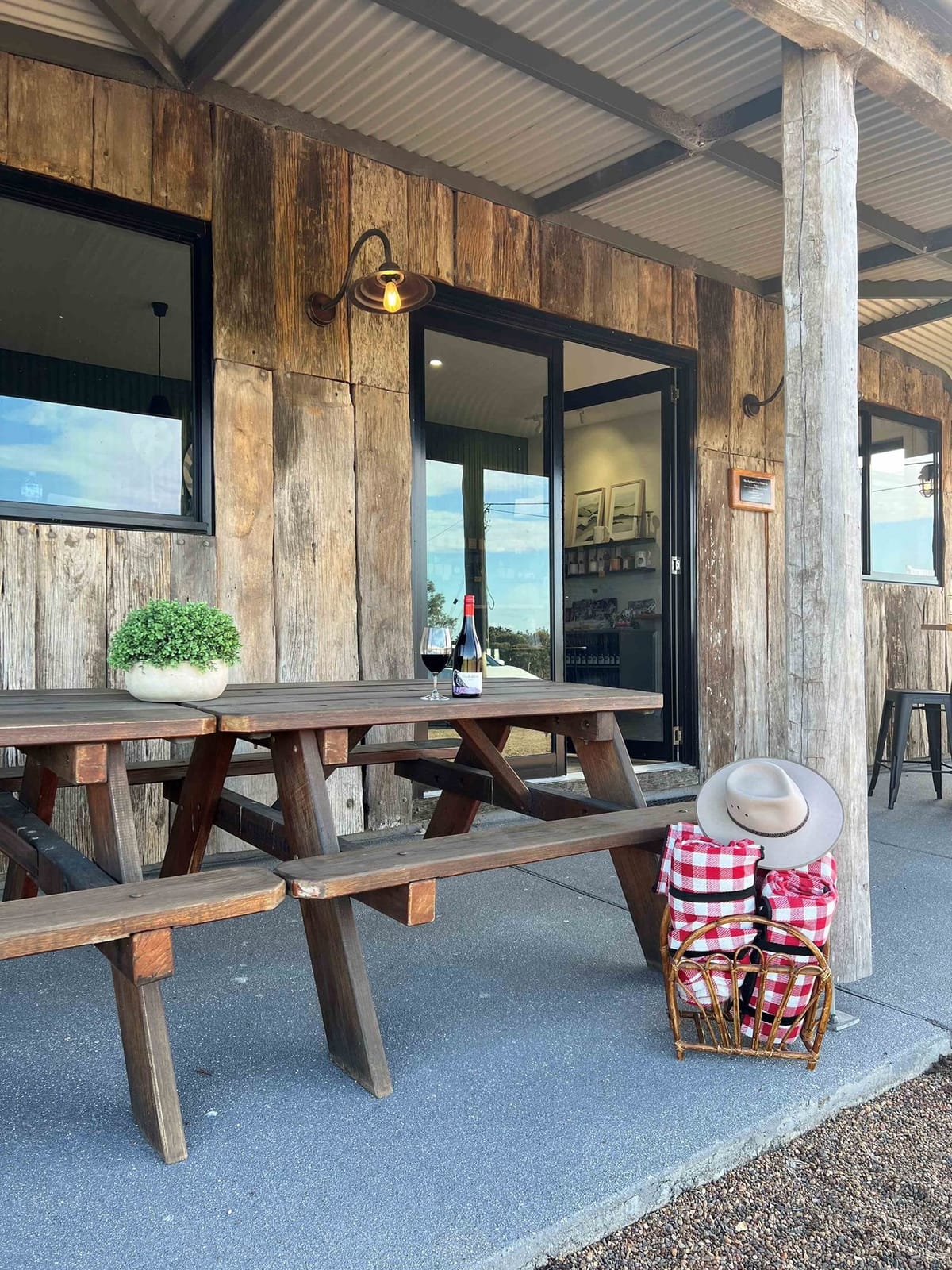 Timber-clad cellar door with picnic tables and gingham rugs at The Parched Crow, Pokolbin, Hunter Valley