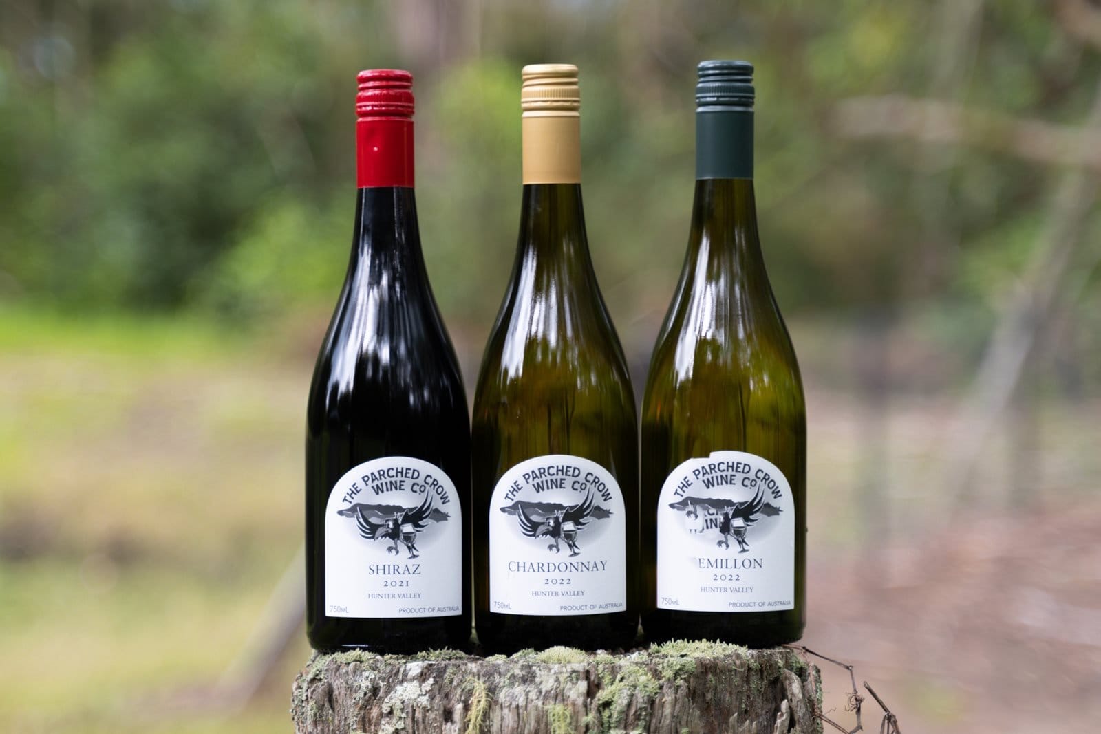 Parched Crow Shiraz, Chardonnay and Semillon bottles standing on a mossy tree stump