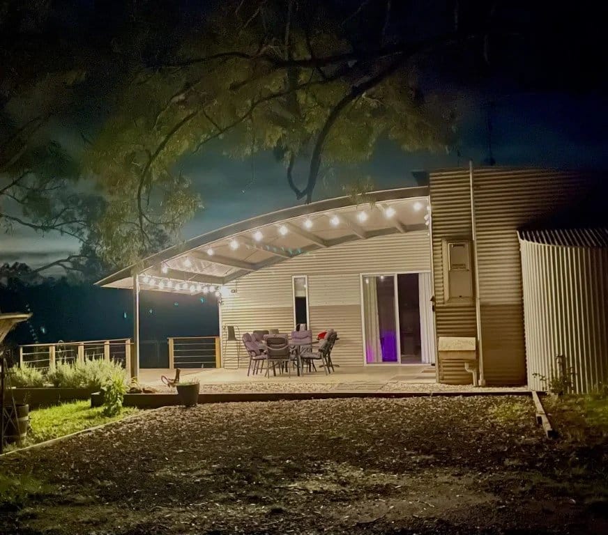 Corrugated iron dwelling with verandah lit at night at The Shedhouse, Broke Fordwich, Hunter Valley
