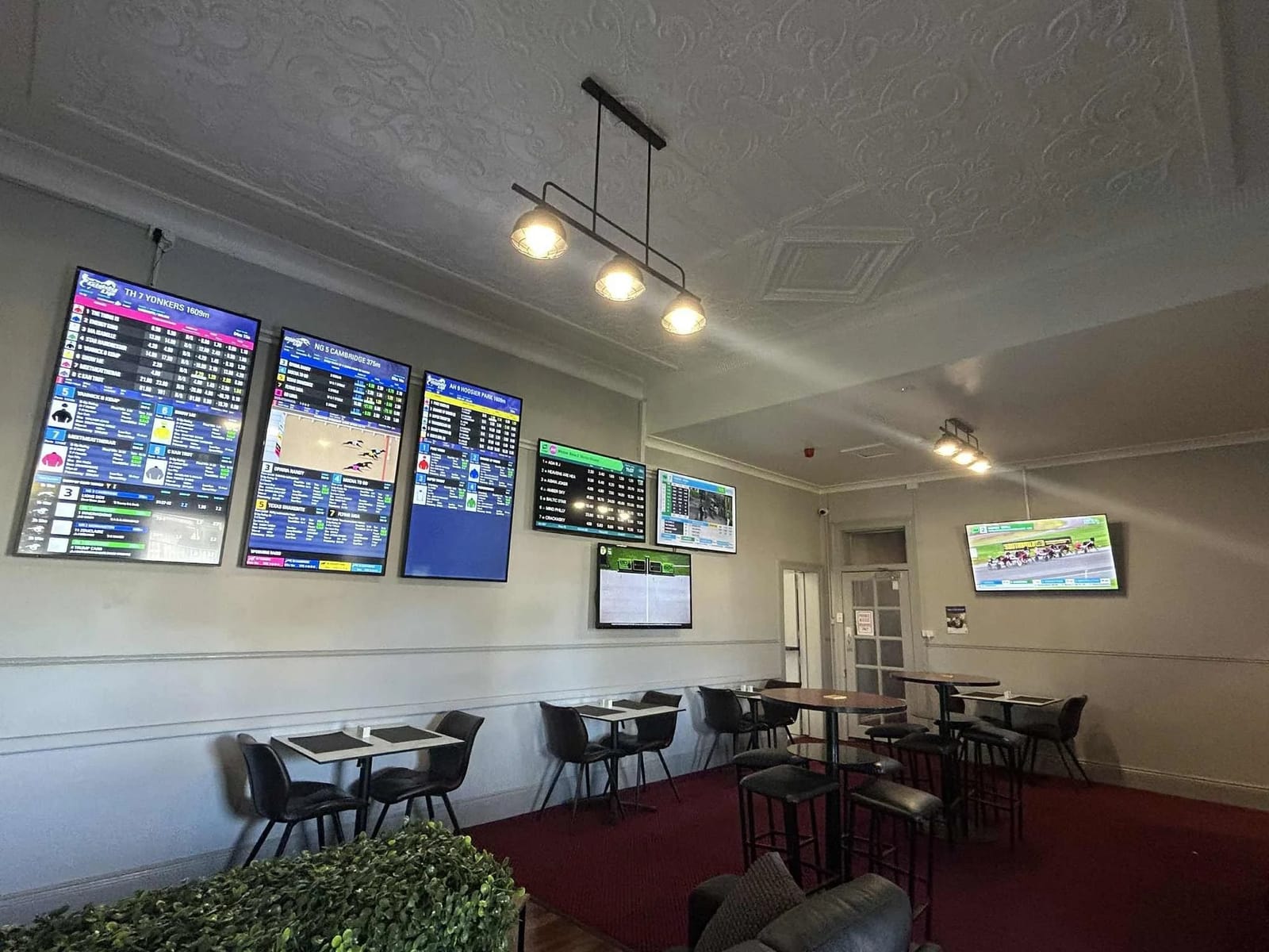 Pub interior with sports screens on walls above tables