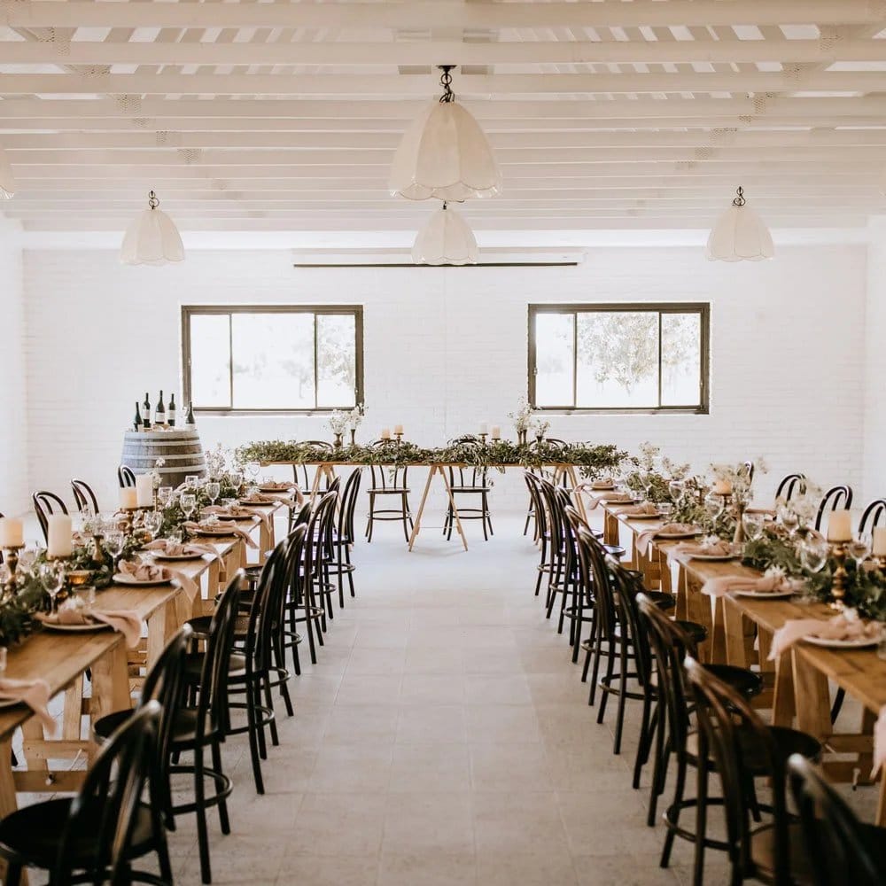Wedding event space with timber tables, pendant lights and florals