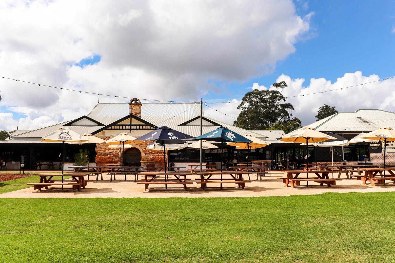 Brewhouse exterior with orange umbrellas and wooden picnic seating at The Valley Brewhouse, Nulkaba, Hunter Valley