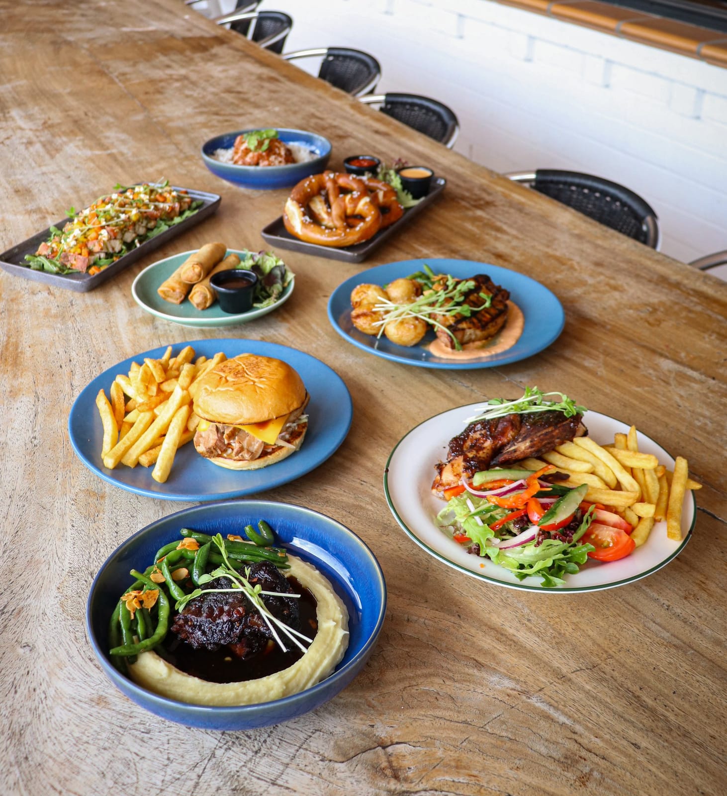 Plated meals including burgers, salads and mains on timber table