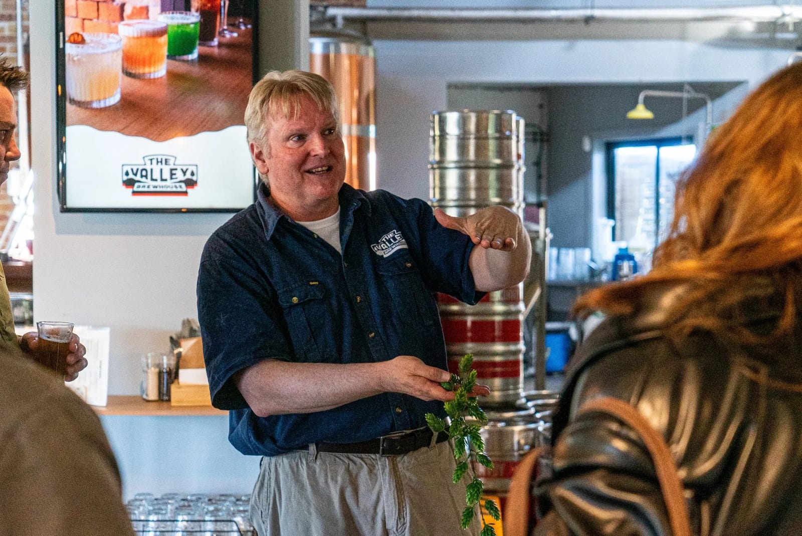 Brewery staff member pouring tasting flight for visitors indoors