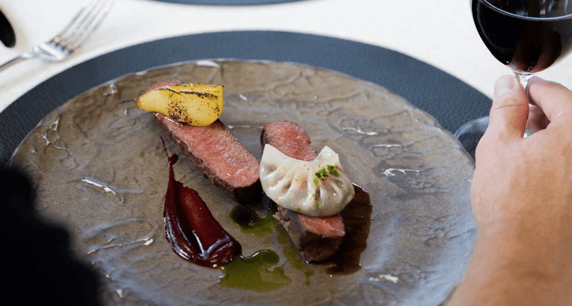 Fine dining plate with rare steak, potato and herb garnish