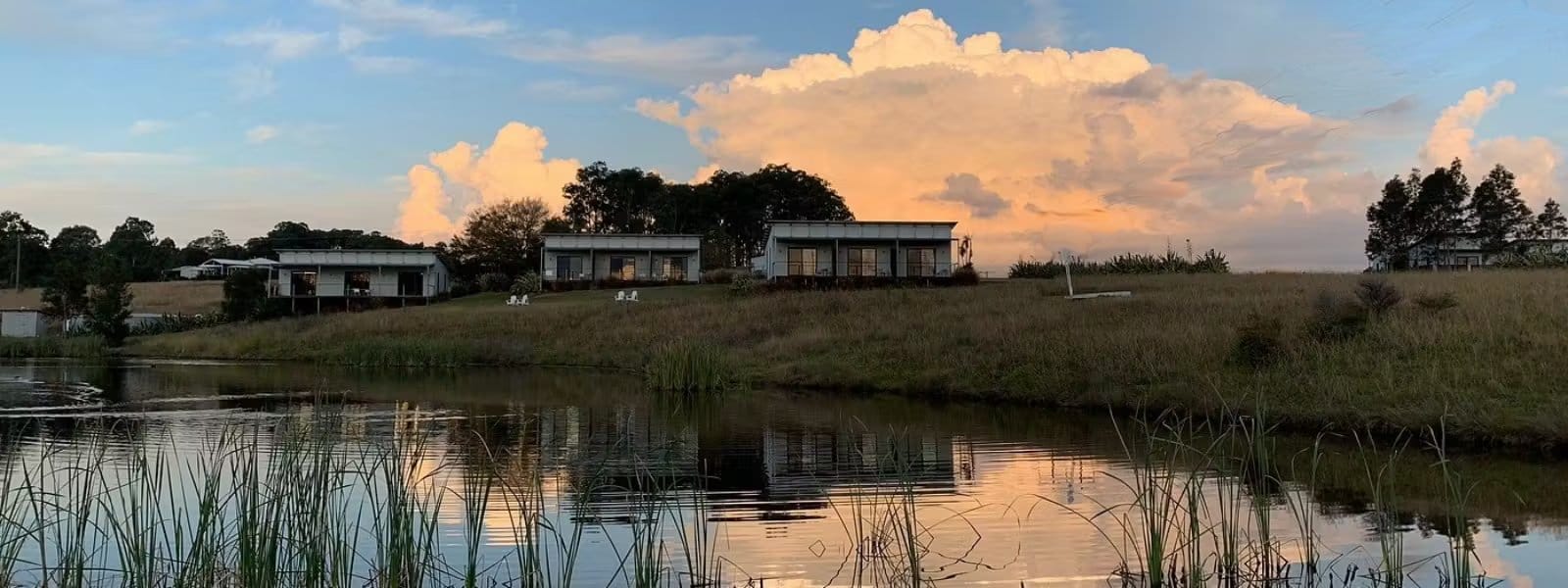 Suites on a rise above reed-fringed dam at sunset at Tonic Hotel, Lovedale, Hunter Valley