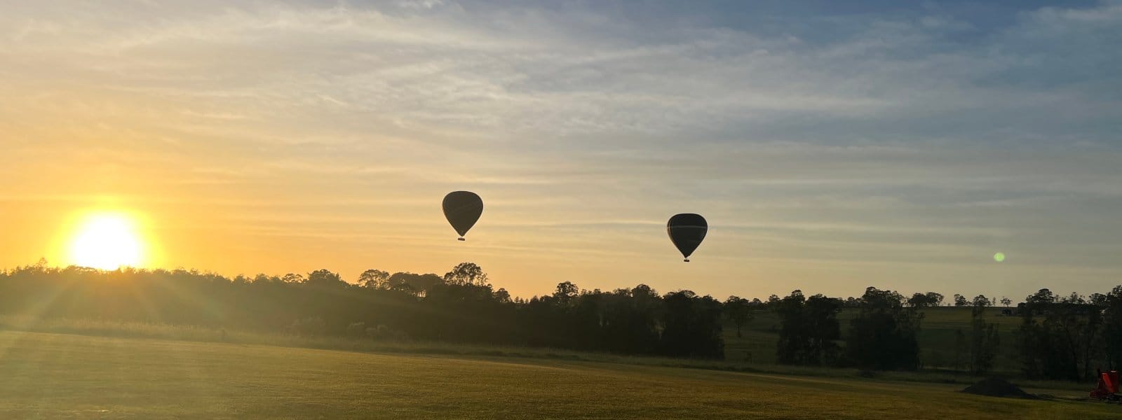 Two hot air balloons over the paddock at sunrise