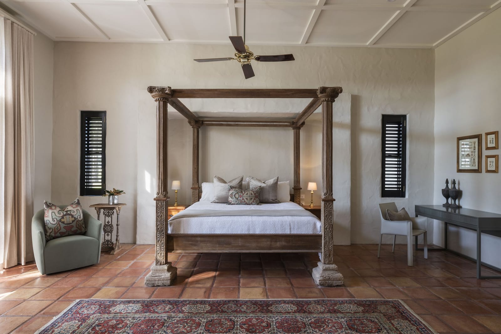 A suite bedroom with a carved four-poster bed on terracotta tiles