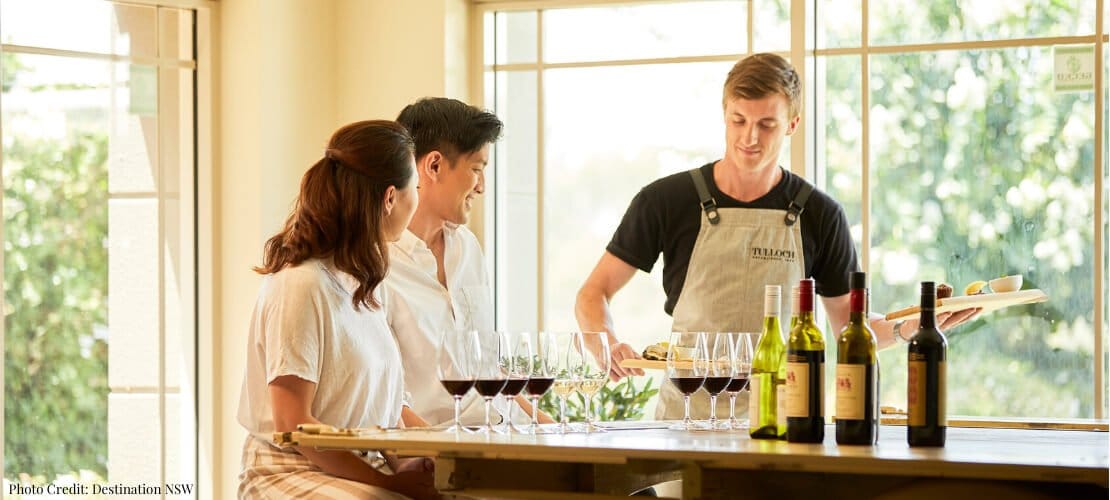 A staff member pours a tasting flight for two guests at the Tulloch cellar door bar.
