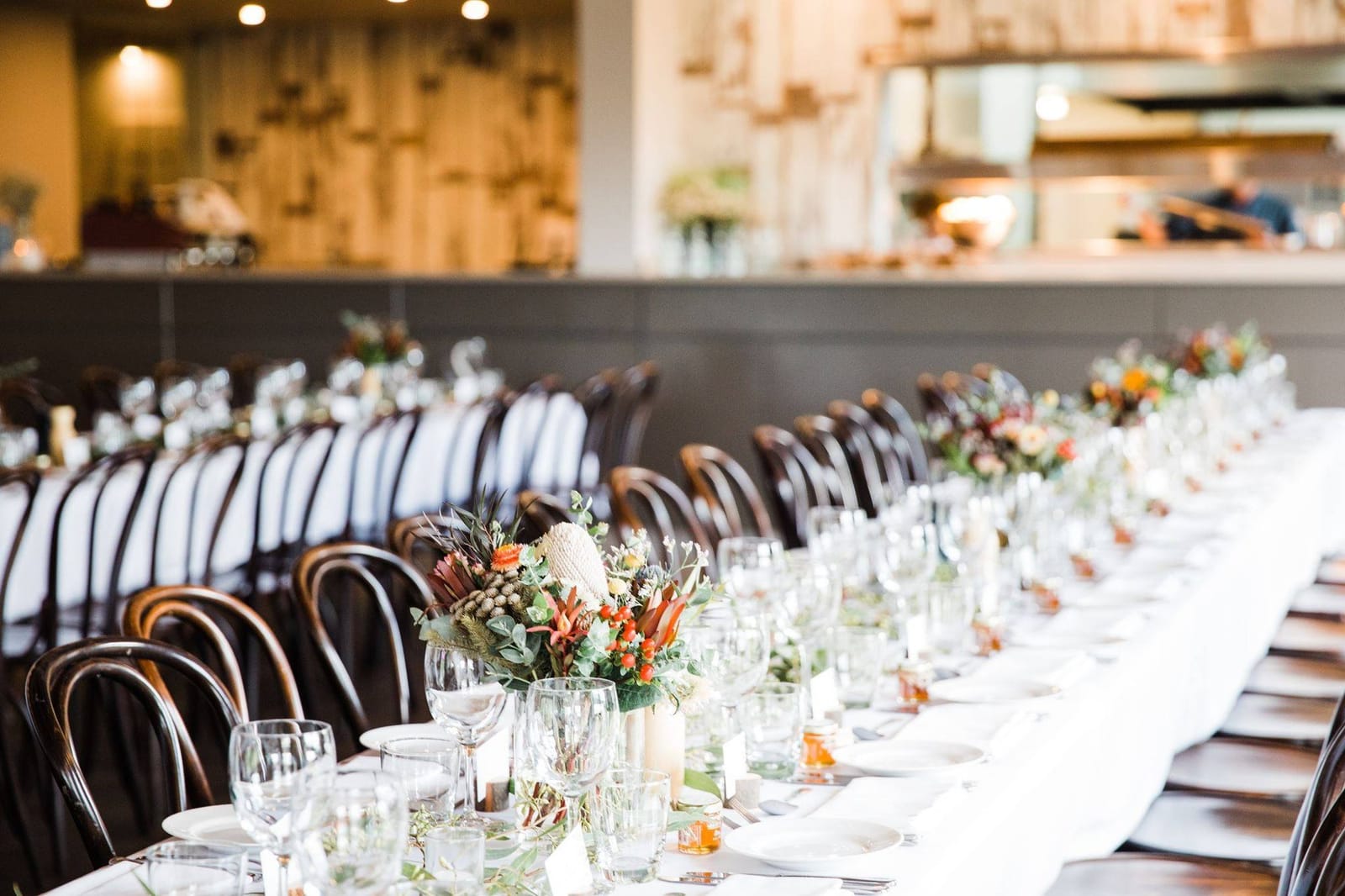 Dining room at Twine Restaurant with bentwood chairs and an open kitchen, set for a private event
