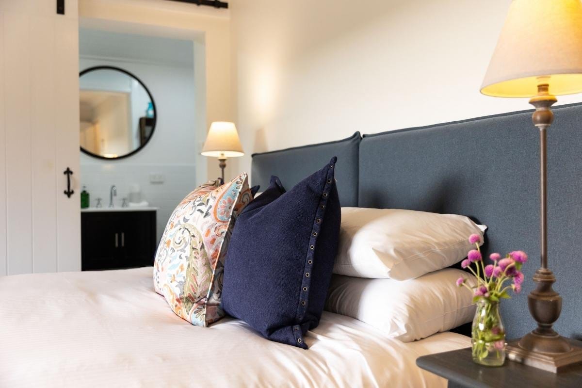 Hotel bedroom with grey upholstered bed and marble ensuite visible
