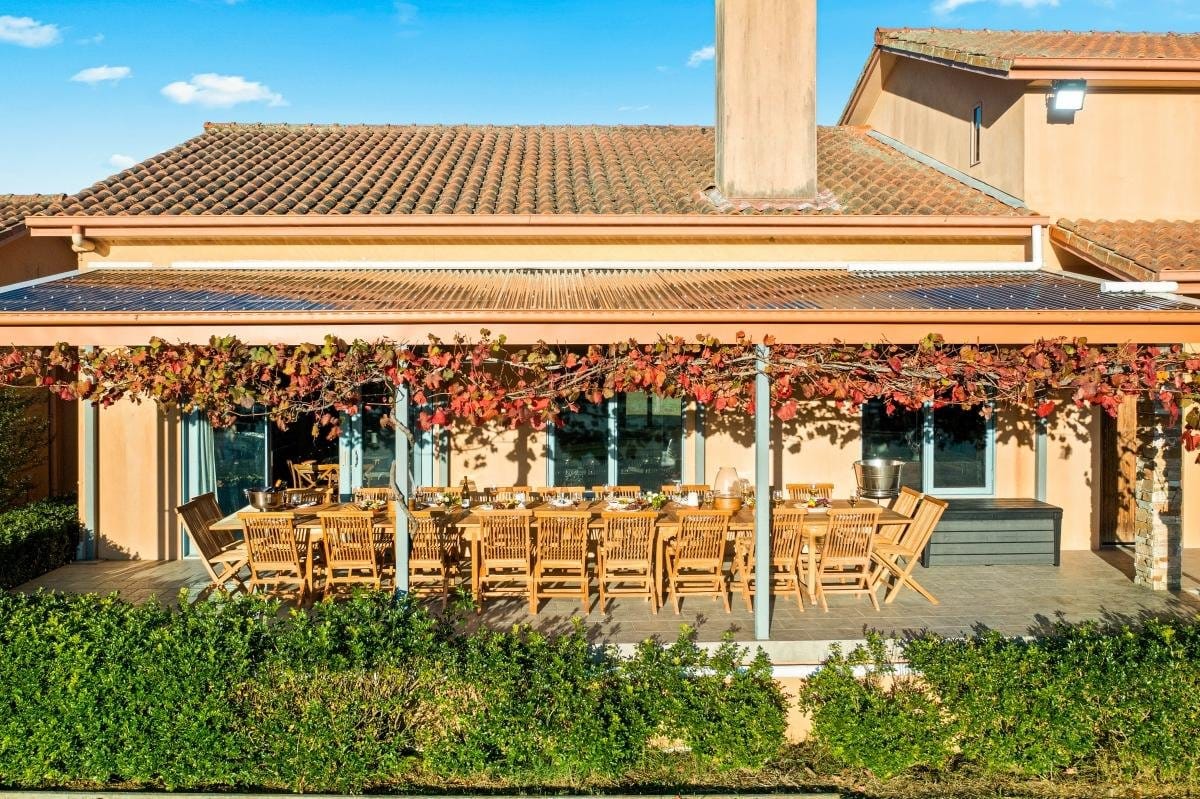 Long outdoor dining table set for a large group on the vine-shaded terrace at Villa Leone
