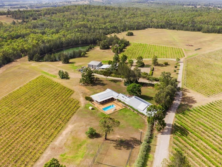 Aerial view of the property showing the homestead, pool, tennis court and surrounding vineyard rows