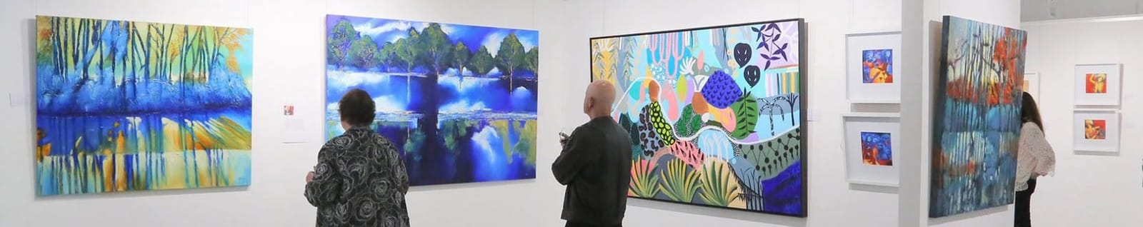 Two visitors looking at large paintings along gallery wall at Watershed Gallery, Pokolbin, Hunter Valley