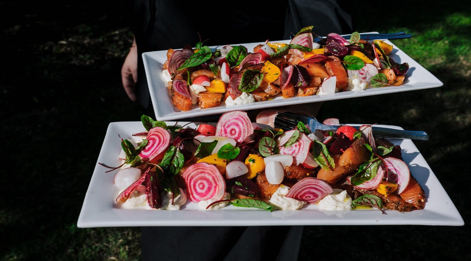 Two white plates of grilled vegetables and seasonal produce