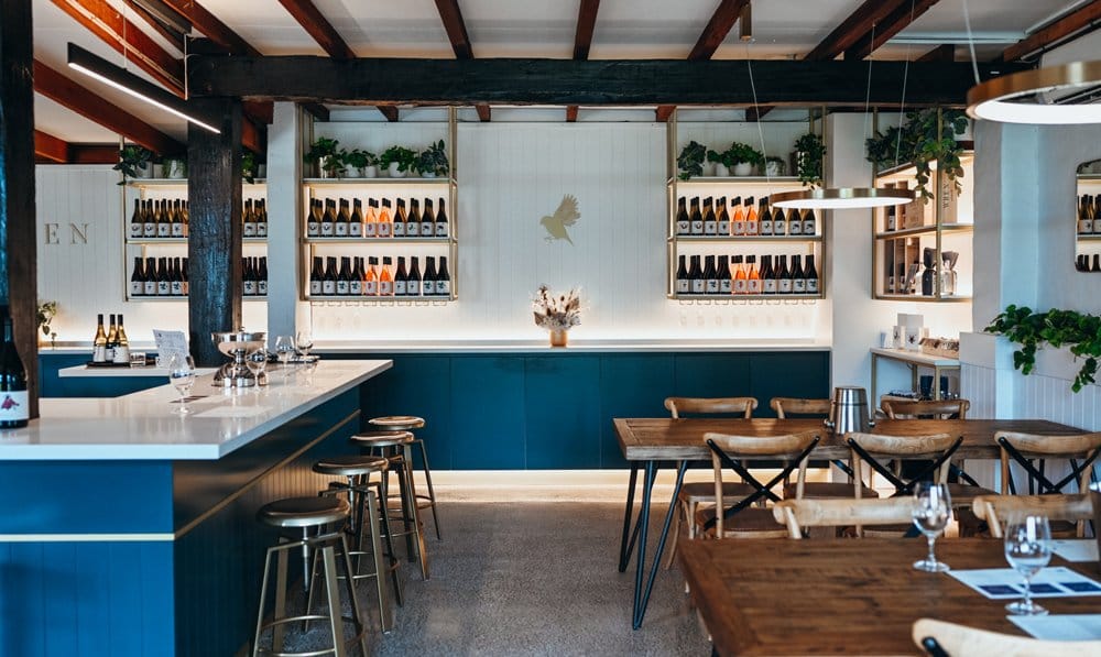 Cellar door interior with blue joinery and shelves of bottles behind bar at Wild Ren, Pokolbin, Hunter Valley