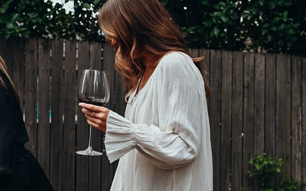 A guest holding a glass of red wine in the courtyard
