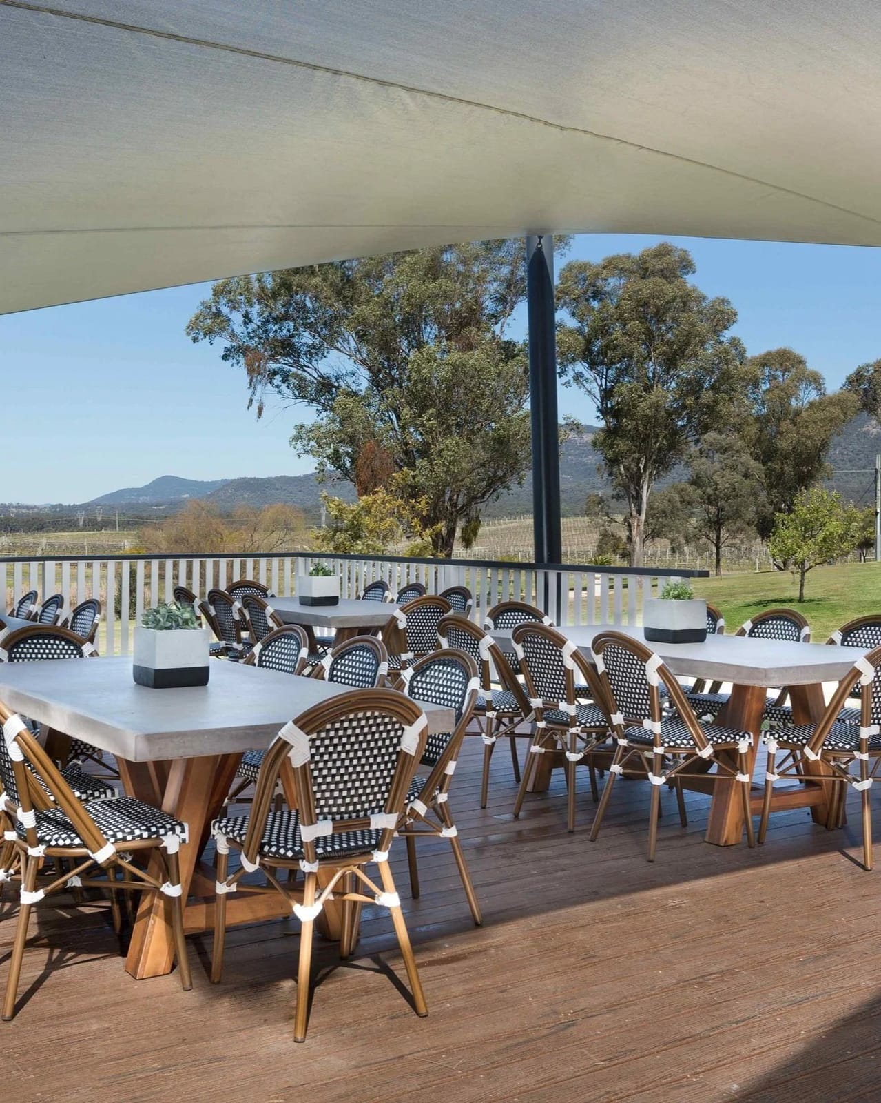 The covered entertaining deck with long tables set for a group, looking over the vineyard