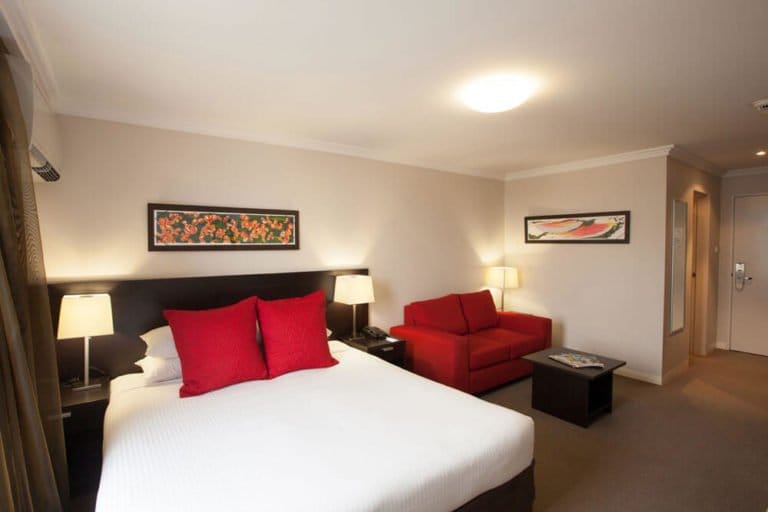 Modern hotel room with queen bed and red cushion accents at Wine Country Motor Inn, Cessnock, Hunter Valley