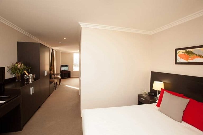 Hotel room hallway with open bedroom and beige carpet