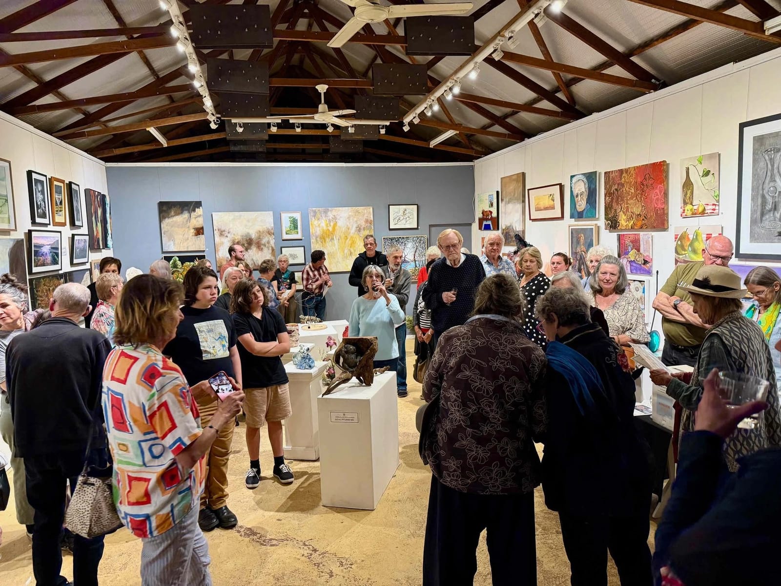 Gallery opening or community event with visitors viewing artworks