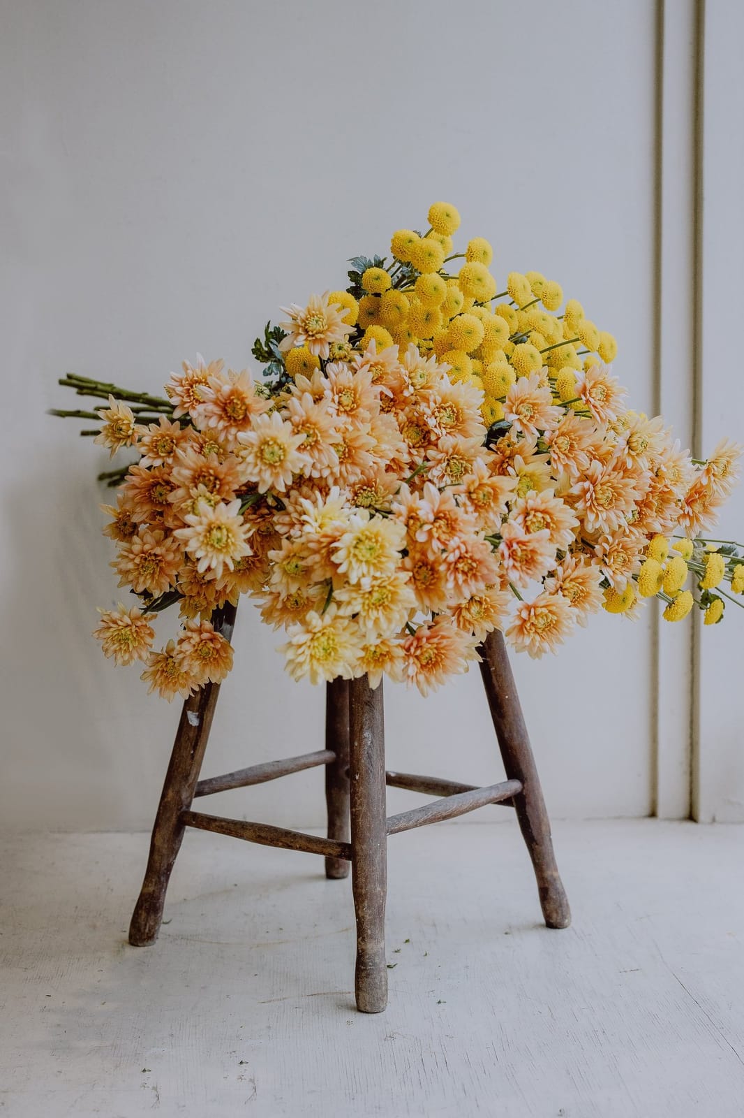 A yellow seasonal arrangement on a stool in the florist space