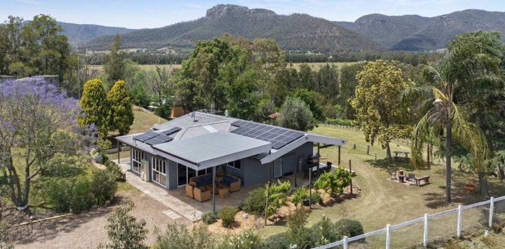 Aerial view of cottage on hillside with Brokenback range behind at Yellowrock Cottage, Broke, Hunter Valley